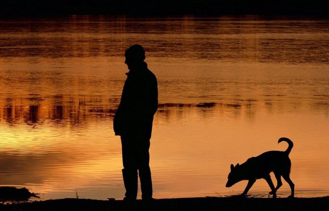 A man and his dog take a walk as sun sets behind the Gorinsee lake in Wandlitz near Berlin on December 27, 2008. Winter brought a sunny day with temperatures around the freezing point to the German capital and the surrounding Brandenburg region.     AFP PHOTO     DDP/THEO HEIMANN    GERMANY OUT (Photo credit should read THEO HEIMANN/AFP/Getty Images)